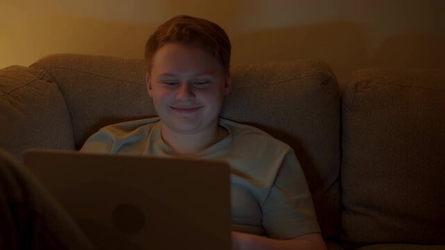 Young Male Seated Comfortably With Laptop. Teenage Boy In Casual Wear Watches Video Content Peacefully