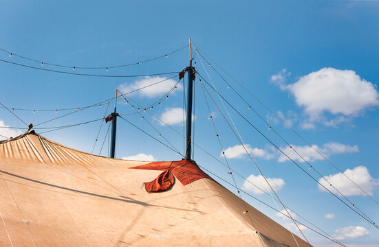 Big Top Circus Tent Spikes and String Lights Against Blue Sky with scattered white clouds.