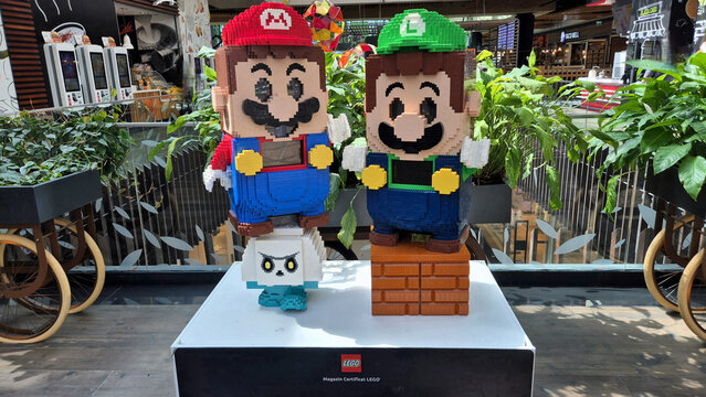Lego statues of Mario and Luigi standing on a Goomba and a brick block inside a brightly lit shopping mall display. Picture taken on April 27, 2026 in Bucharest, Romania.
