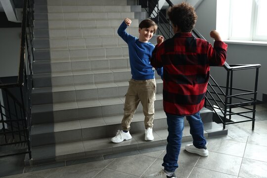 Bullying. Boy fighting with his African American classmate in school