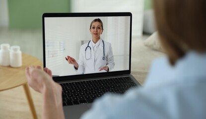 Fototapeta premium Telemedicine. Woman having online consultation with doctor via laptop at home, closeup
