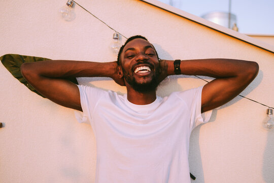 Black man smiling and relaxing with hands behind head