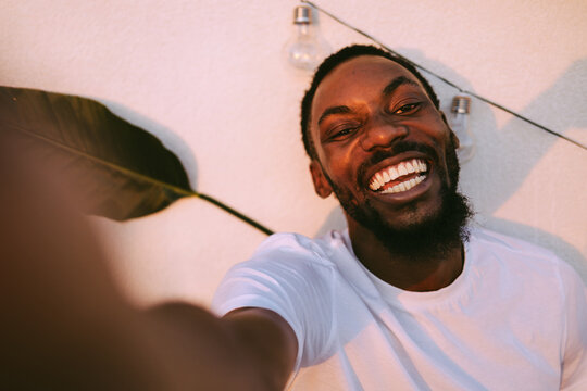 Happy young black man taking selfie portrait smiling broadly