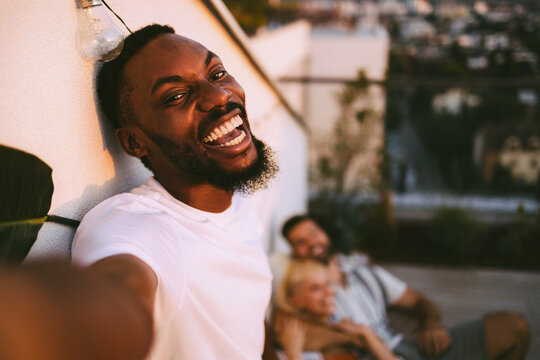 Cheerful man taking selfie with friends on rooftop