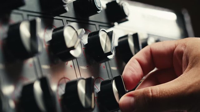Music studio close up, Close up hands shot of sound engineer using mixing console, remote control for adjusting sound, audio mixer. Musician creates music, makes remix for DJ set. Sound recording