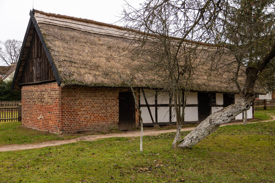 Traditional thatched roof building preserving history in Kluki, Poland.