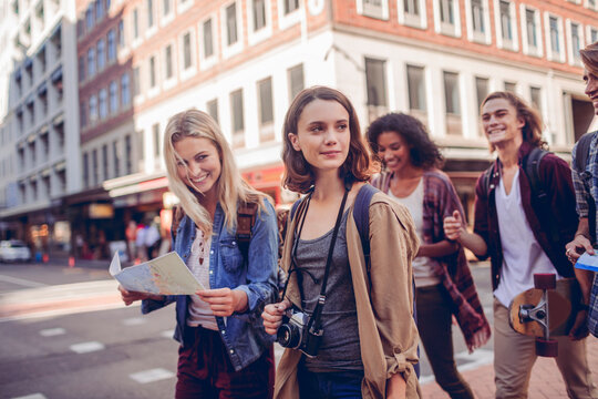 Young friends exploring city street with map and camera