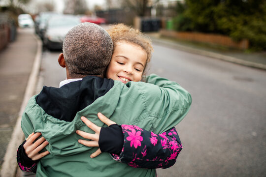 Father and daughter hugging on suburban street