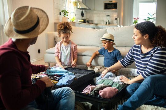 Family packing suitcase together at home for vacation
