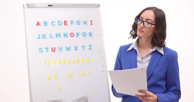 Teacher in blue blazer stands near alphabet board thinking. Confused educator searches correct word answer suddenly remembering needed phrase