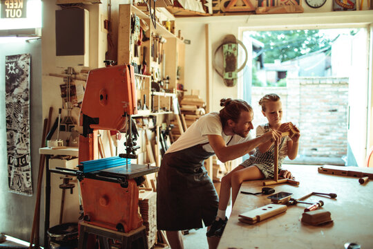 Father teaching daughter woodworking in home workshop