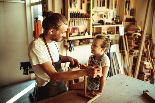 Father teaching daughter woodworking in home workshop