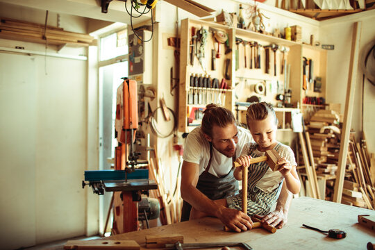 Father teaching daughter woodworking in home workshop