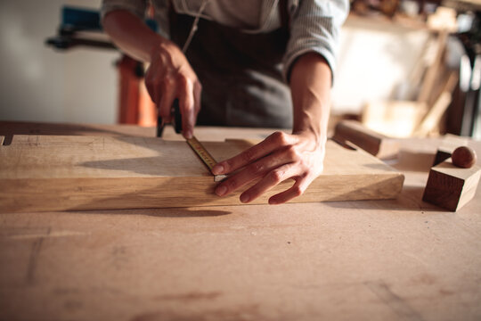 Carpenter measuring wood plank in workshop