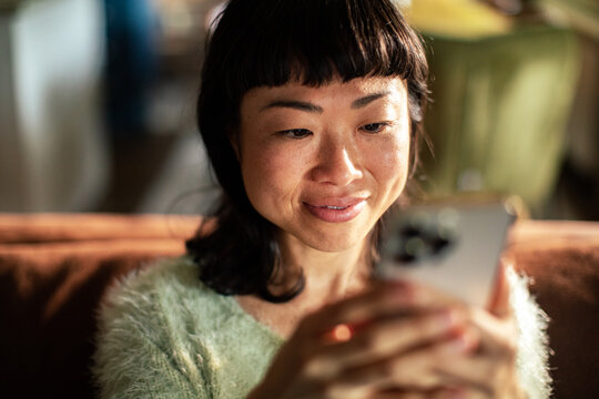Smiling woman using smartphone at home