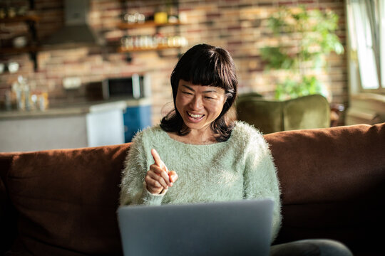 Smiling woman video chatting on laptop at home