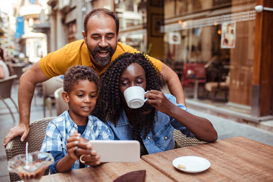 Parents and child using tablet at outdoor cafe