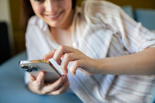 Smiling young woman texting on smartphone at home