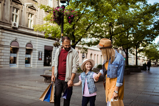 Parents and daughter shopping together on city street