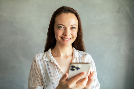 Smiling woman using smartphone at home indoors