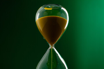 A green hourglass counting down against a green background, representing the concept of working with time and using time most efficiently.