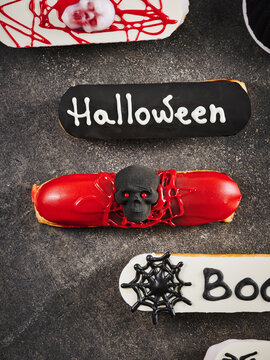 This image showcases Halloween-themed eclairs decorated with skulls and spider motifs