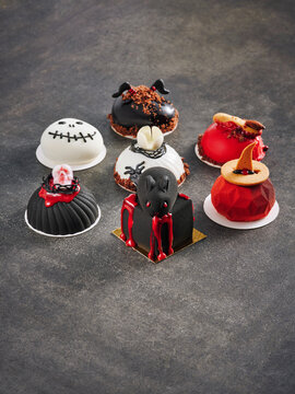 The image showcases a variety of Halloween-themed desserts, including mini cakes designed with spooky decorations