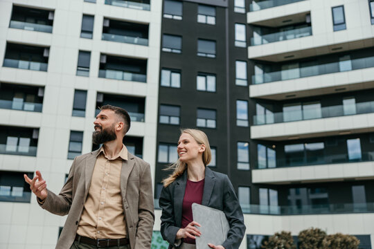 Real estate agents discussing property in front of modern apartments