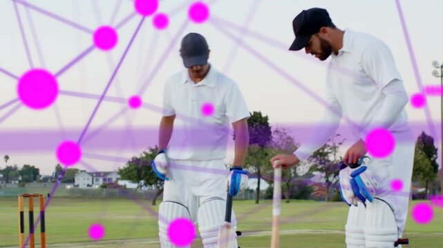 Two batsmen adjusting bats, partner approaching, joining crease preparing to bat under pink overlay