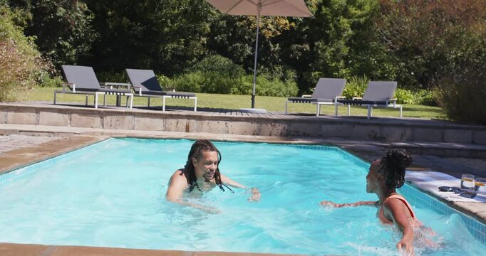 African American couple playing in yard pool in swimsuits after man removing goggles, hugging