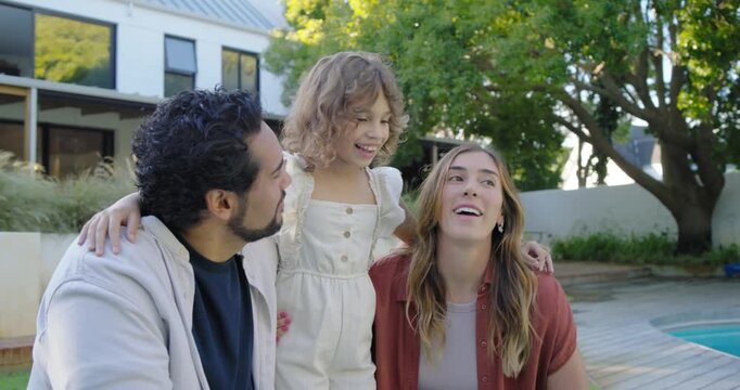 Family of three listening and smiling while child speaking and gesturing on wooden deck beside pool