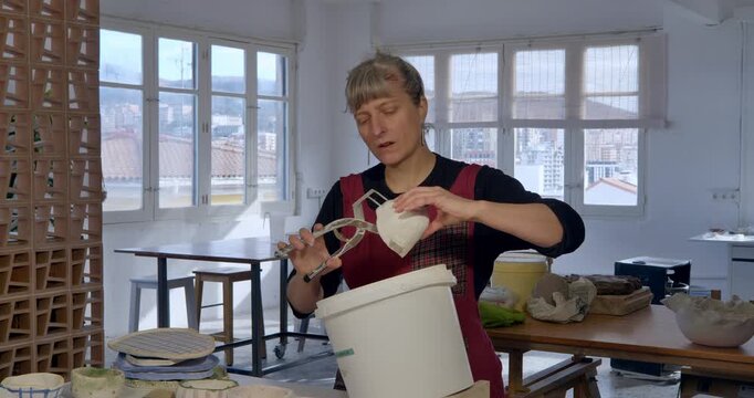 Creative Craft: A skilled artist intently crafts a ceramic piece, working within a spacious workshop filled with natural light, showcasing the artistry of creation.