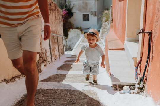 Close up on legs of father and toddler walking in town on summer holiday.