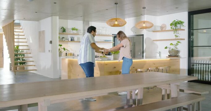 Couple entering kitchen, taking hands and dancing playfully, trading leads, finishing facing island