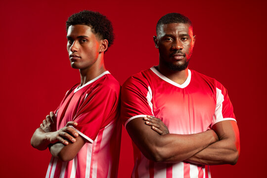 African American male teammates standing back-to-back in studio in red-and-white striped jerseys