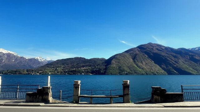 Lake como waterfront with mountains and clear blue sky over water and scenic roadside view