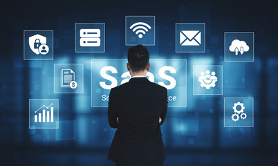 A business professional stands focused on the digital representation of Software as a Service, surrounded by various icons illustrating cloud-based technology and services. Ledger © InfiniteFlow