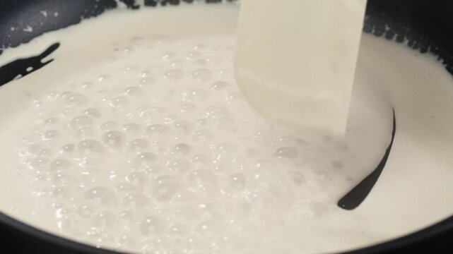 Boiling cream, boil yogurt swirl milk white lotion splash on pan. Cooking white sauce.