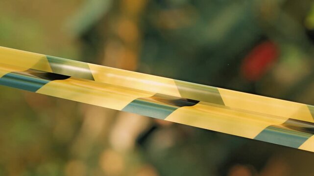 Close up shot of yellow black striped caution tape. Diagonal composition creates visual tension. Soft light highlights plastic texture. Blurred background suggests outdoor setting restricted area