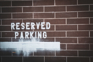 Obraz premium Reserved parking stencil sign on urban alley brick wall