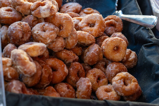 A large basket filled with warm, golden-brown mini donuts covered in a sweet, glistening sugar glaze.