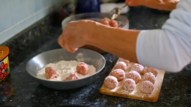 Scooping seasoned ground meat with spoon into flour plate, step by step homemade meatballs preparation, traditional recipe process, home cooking scene, food preparation workflow