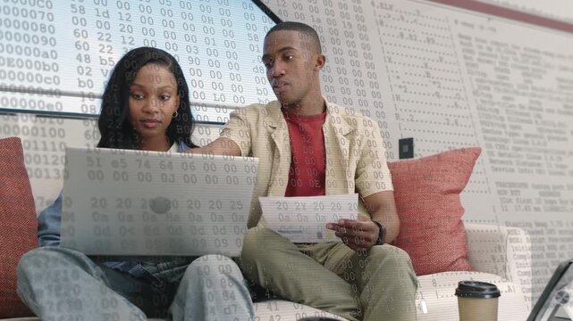 Man pointing, woman checking paper and laptop verifying finances with numeric overlay appearing