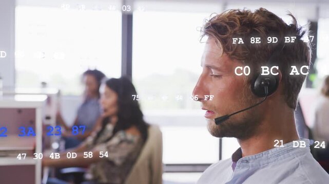 Male call center agent taking call speaking into headset team typing hex codes floating over agents