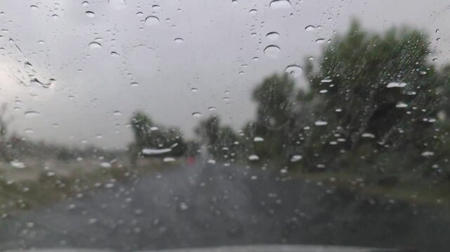 Raindrops accumulating on a car windshield while driving through a lush forest road during a heavy storm 120fps 4K Slow Motion Captured in Cinematic High-Detail Clip