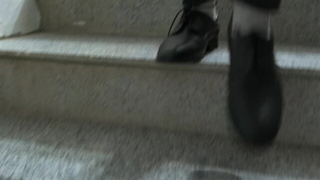 Front view of person walking down stairs in shoes, showing step movement, descent motion, urban environment, daily activity, footwear detail, motion blur, perspective of walking and human movement