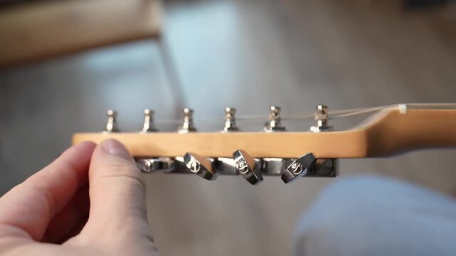 A man Tuning his guitar and playing it. Top lock tuners on double cut electrical guitar.