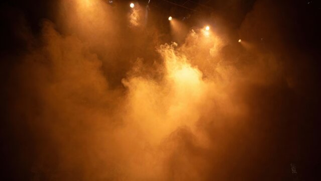 Warm lights pierce swirling fog in a dim arena