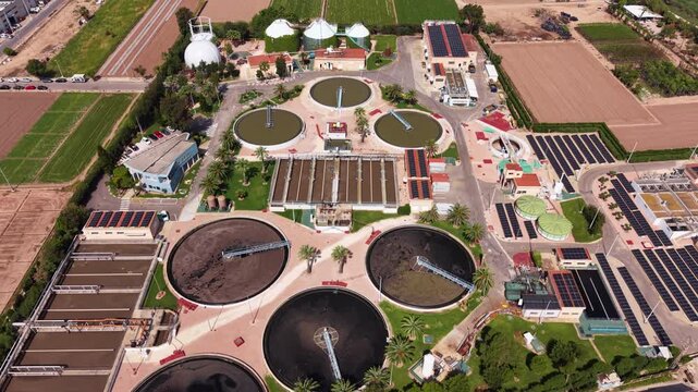 Aerial view of modern wastewater treatment plant featuring circular clarifiers, anaerobic digesters, biogas domes, biological aeration tanks, solar photovoltaic panels, and sludge treatment facilities