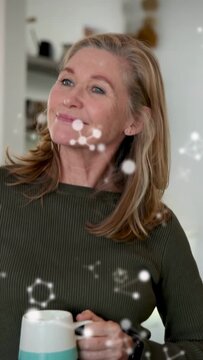 Vertical video: Mature woman sipping mug, health dots mapping face showing wellness, camera closing